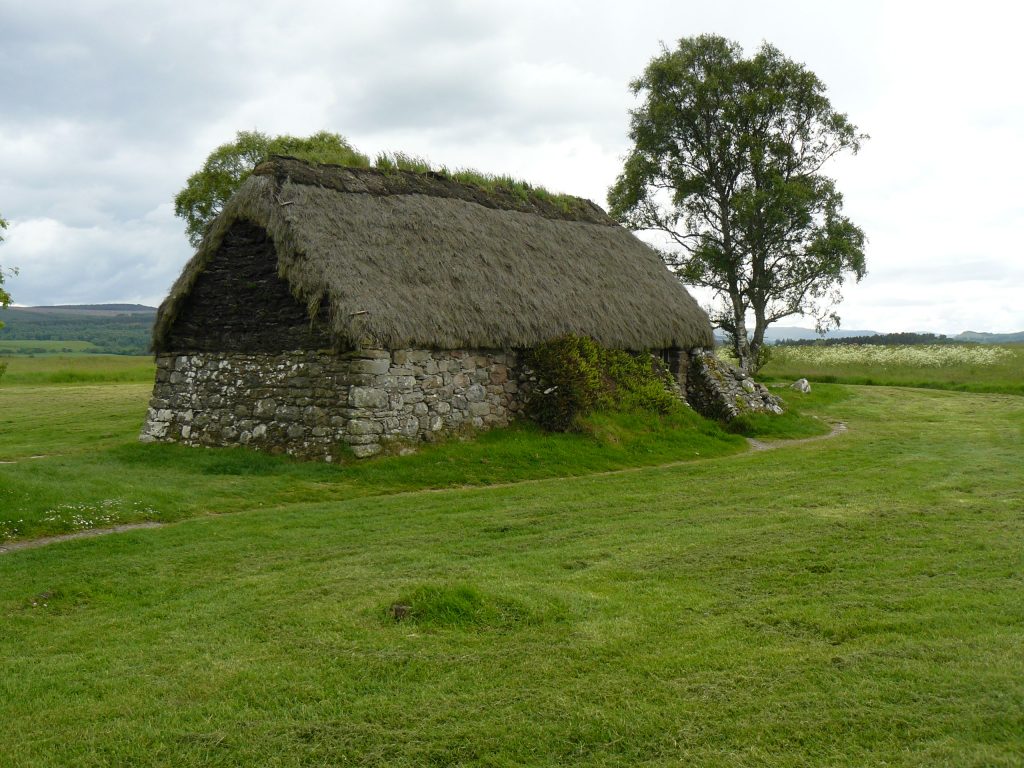 Steinhütte mit Reeddach auf einer Wiese